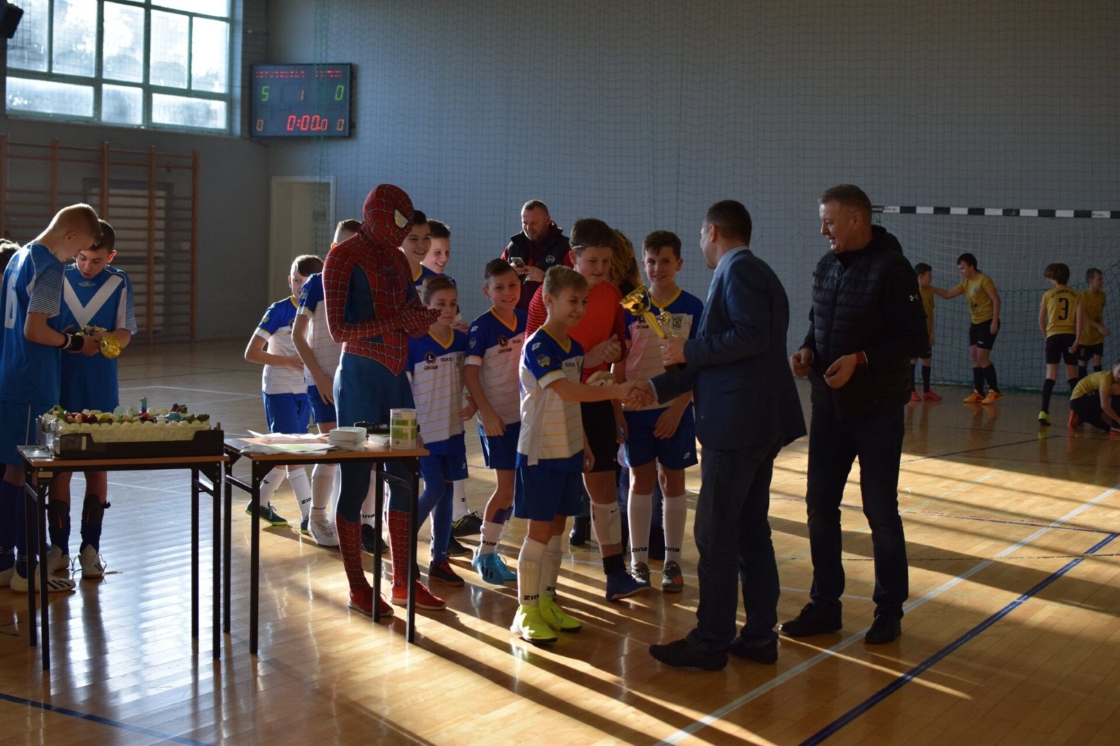 zdjęcie przedstawia wójta rafała plezie wręczającego puchar chłopcowi na turnieju