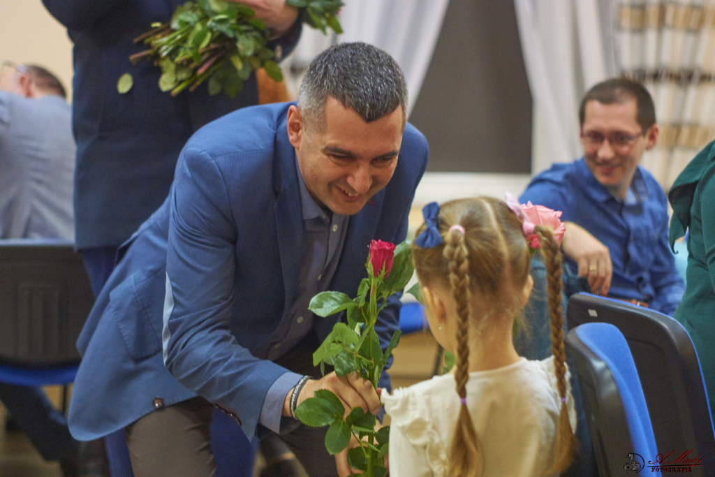 zdjęcie przedstawia wójta rafała plezie wręczającego różę dziewczynce
