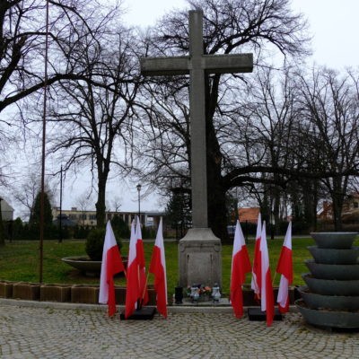 Zdjęcie przedstawiające krzyż i flagi polskie