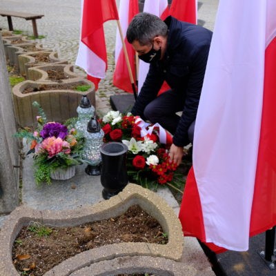 zadjęcie przedstawiające Wójta Rafała Plezię składającego kwiaty pod krzyżem